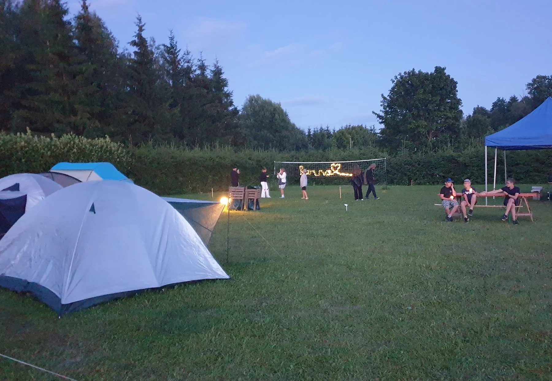 Camping area in the evening light, tents and a shelter with string lights