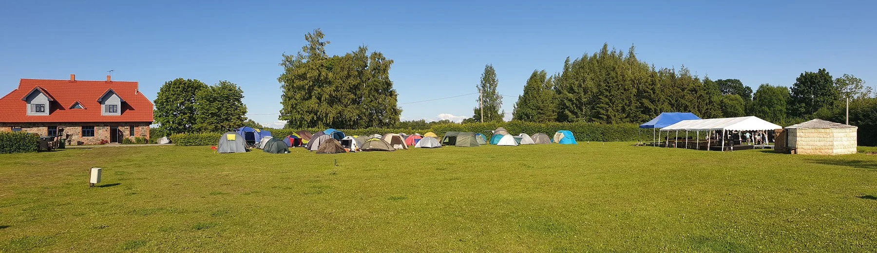 Tents in a row at the edge of the camping area on a summer lawn