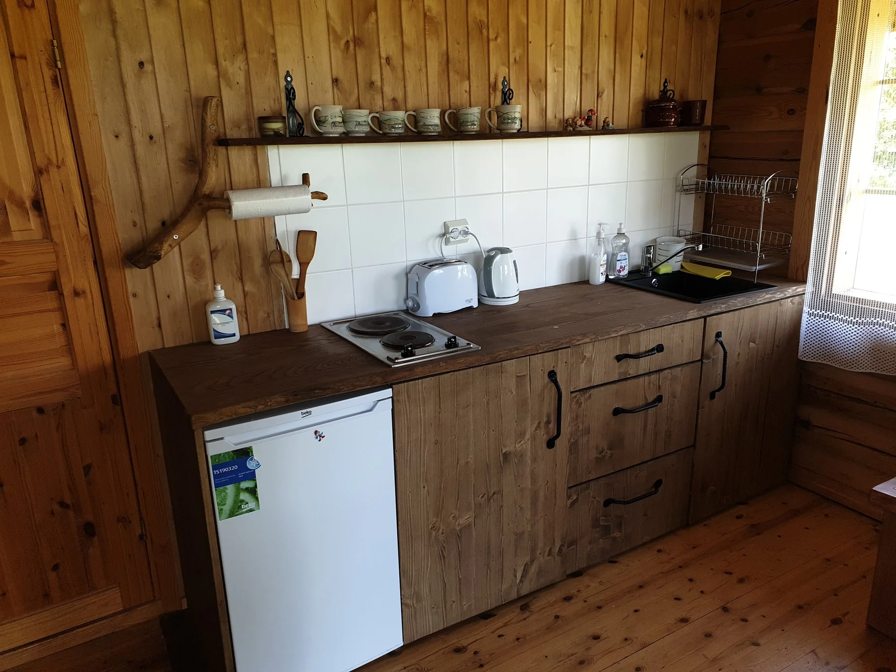Kitchenette with a fridge, cooker and tableware
