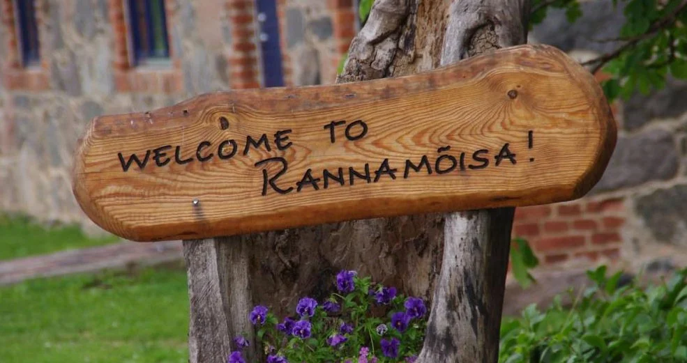 Puidust silt kirjaga „Welcome to Rannamõisa!“ lillede vahel